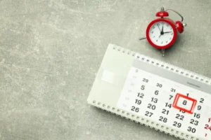 an analogue clock and a calendar on a table