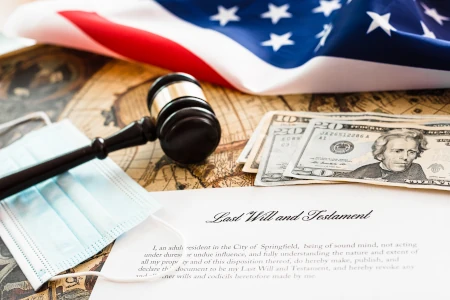 probate in North Carolina. an American flag, a gavel, money, a medical mask and a testament on a wooden desk