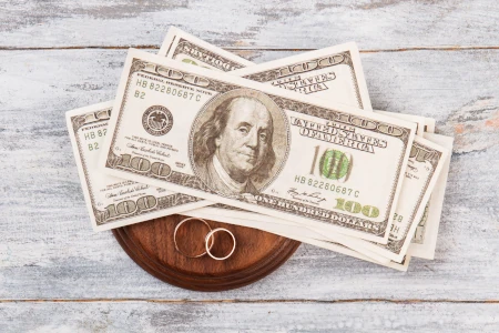 How expensive is a divorce? American currency and two rings lying on a gavel block on a desk